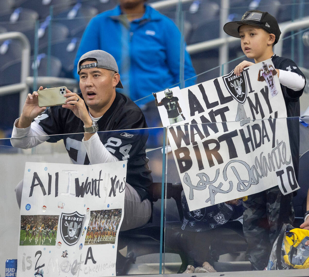 Raiders fans hold up signs before an NFL game against the Los Angeles Rams at SoFi Stadium on T ...