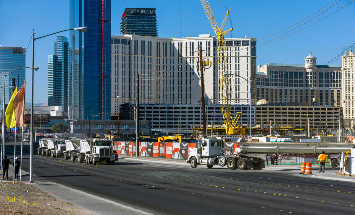 Rock trucks line up to enter and exit the construction on Formula One land along E. Harmon Ave. ...