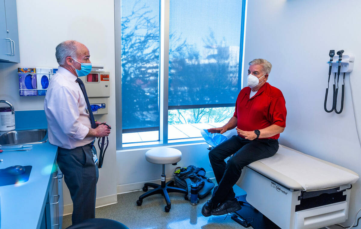 Dr. Charles Bernick, left, talks with clinical trial participant Bob Lathrop before he receives ...
