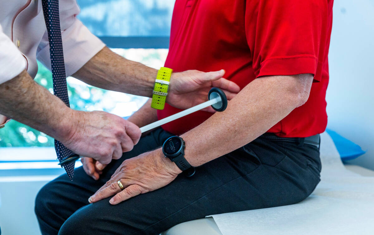 Dr. Charles Bernick, left, checks the reflexes of clinical trial participant Bob Lathrop before ...