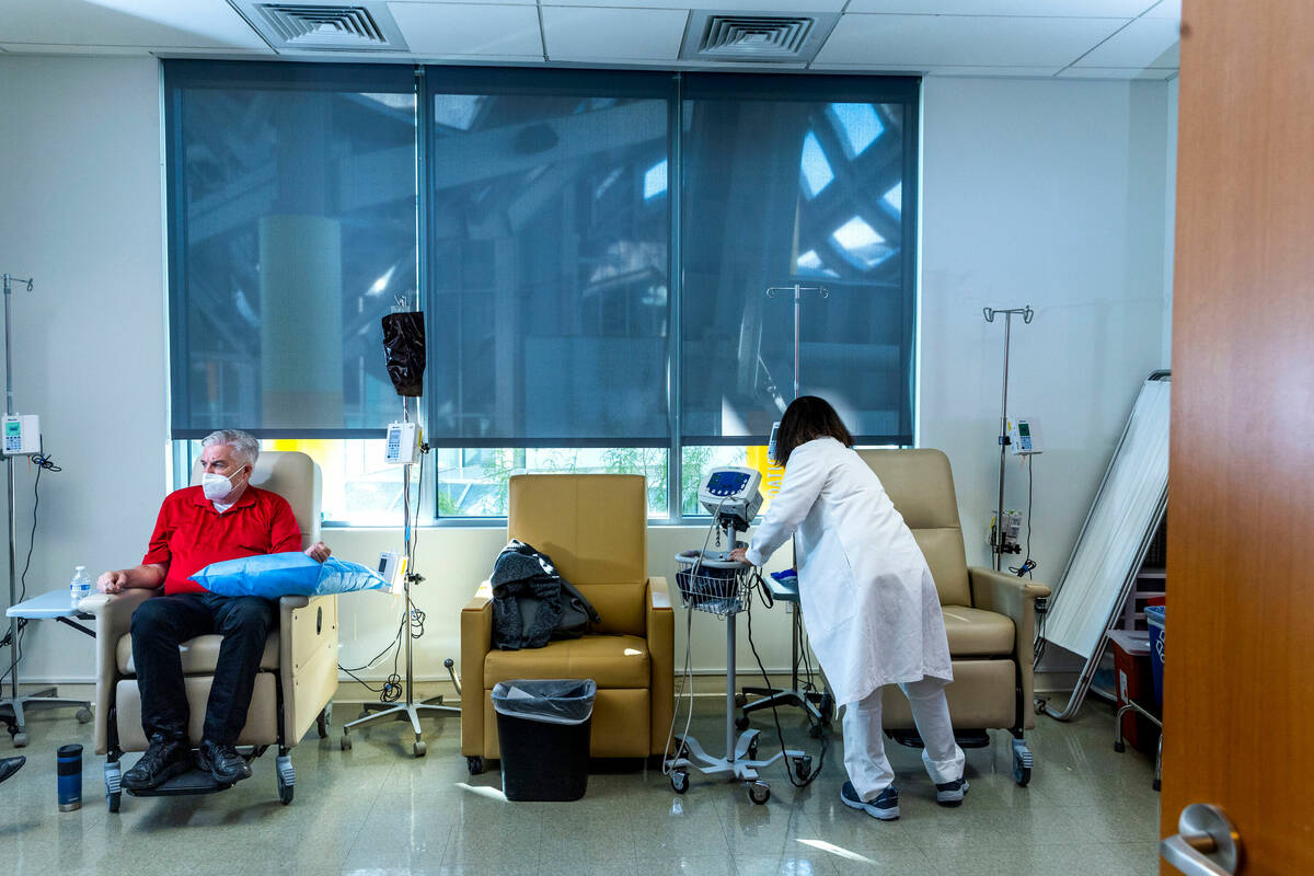 Clinical trial participant Bob Lathrop, left, sits comfortably as infusion room RN Betty Romero ...
