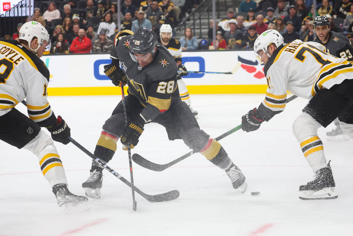 Golden Knights left wing William Carrier (28) battles for the puck between Boston Bruins center ...