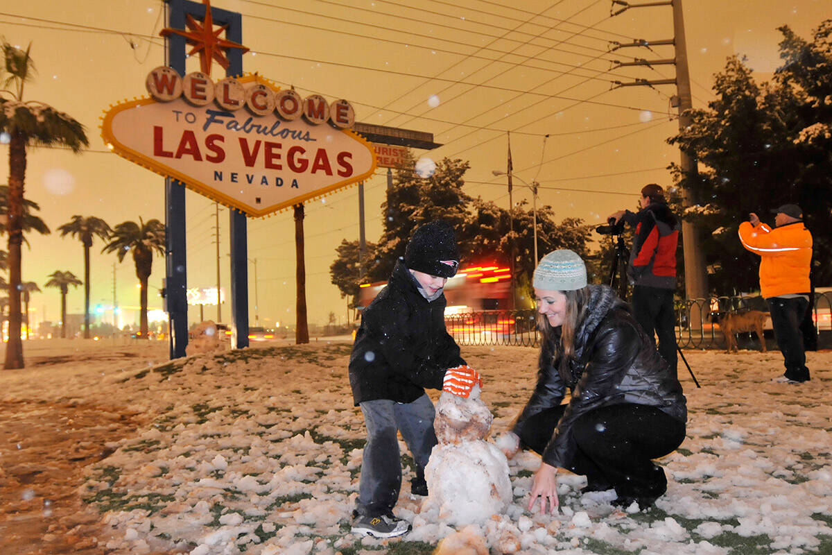 Landen Severson, 6, and his mom, Carly Ward, construct a snowman at the foot of the Welcome to ...