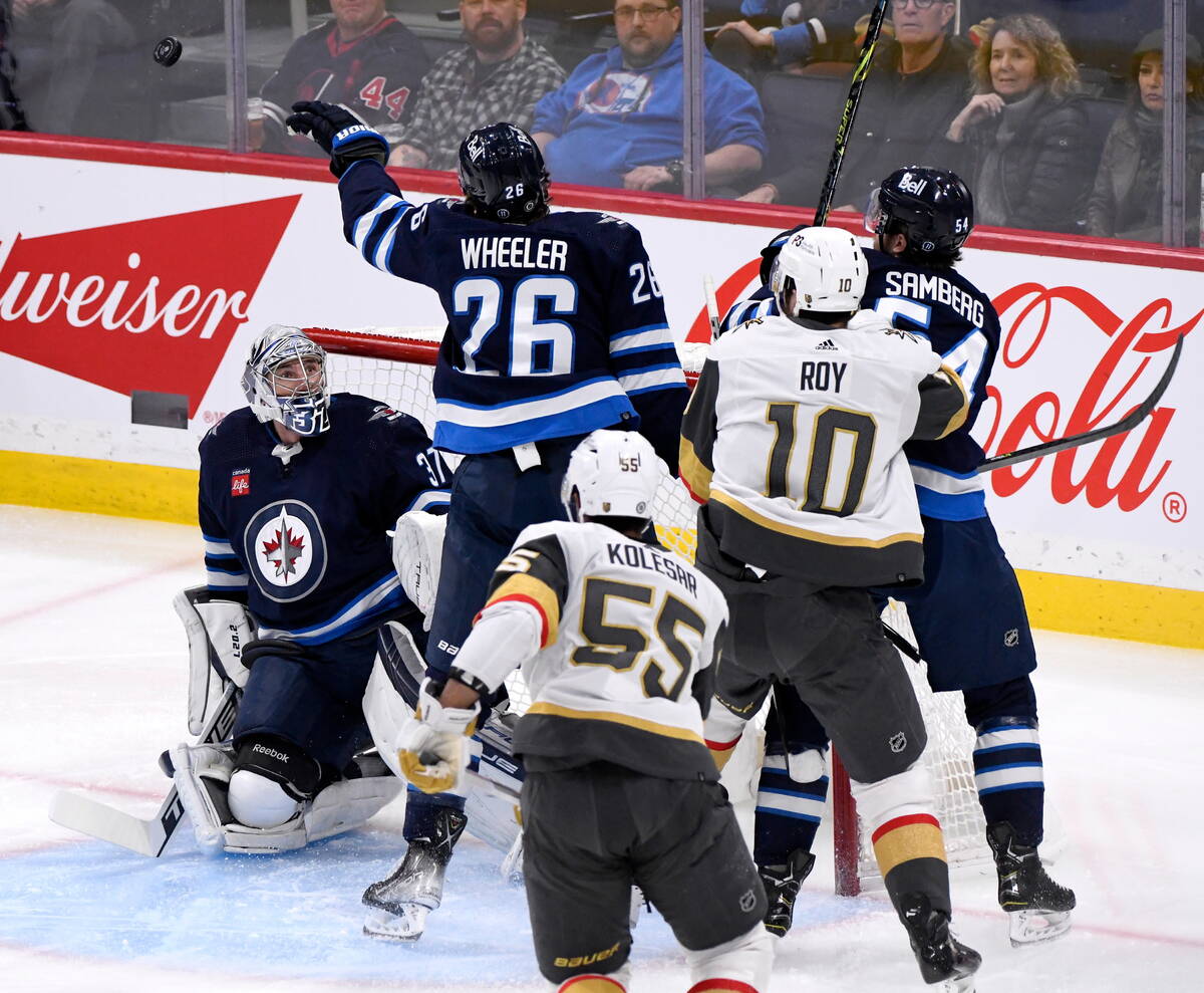 Winnipeg Jets' Blake Wheeler (26) reaches for a loose puck in front of goaltender Connor Helleb ...