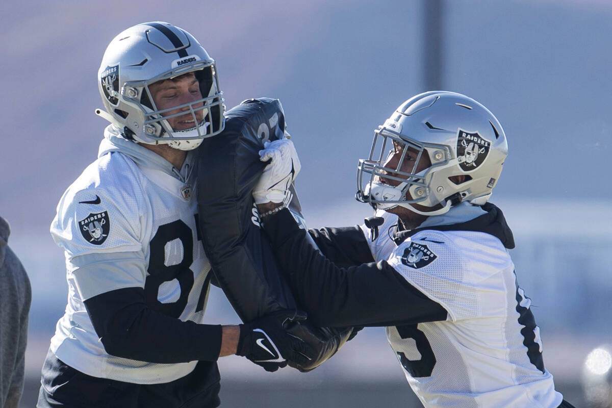 Raiders tight end Foster Moreau (87), left, holds pads as tight end Darren Waller (83) drills d ...