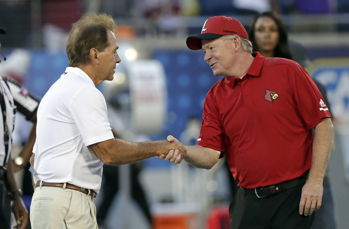 Alabama head coach Nick Saban, left, greets Louisville head coach Bobby Petrino at midfield bef ...