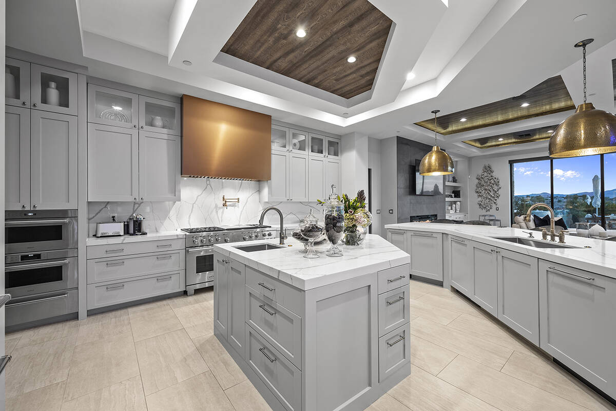 The kitchen features custom cabinetry, central island and unique shaped counter with quartz cou ...
