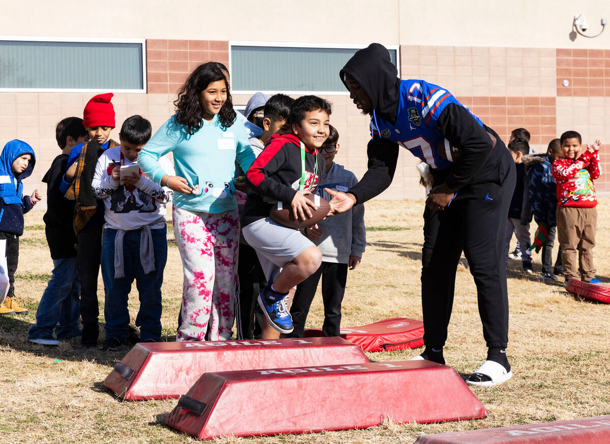 Florida Gators linebacker Scooby Williams hands the ball to C.P. Squires Elementary School stu ...