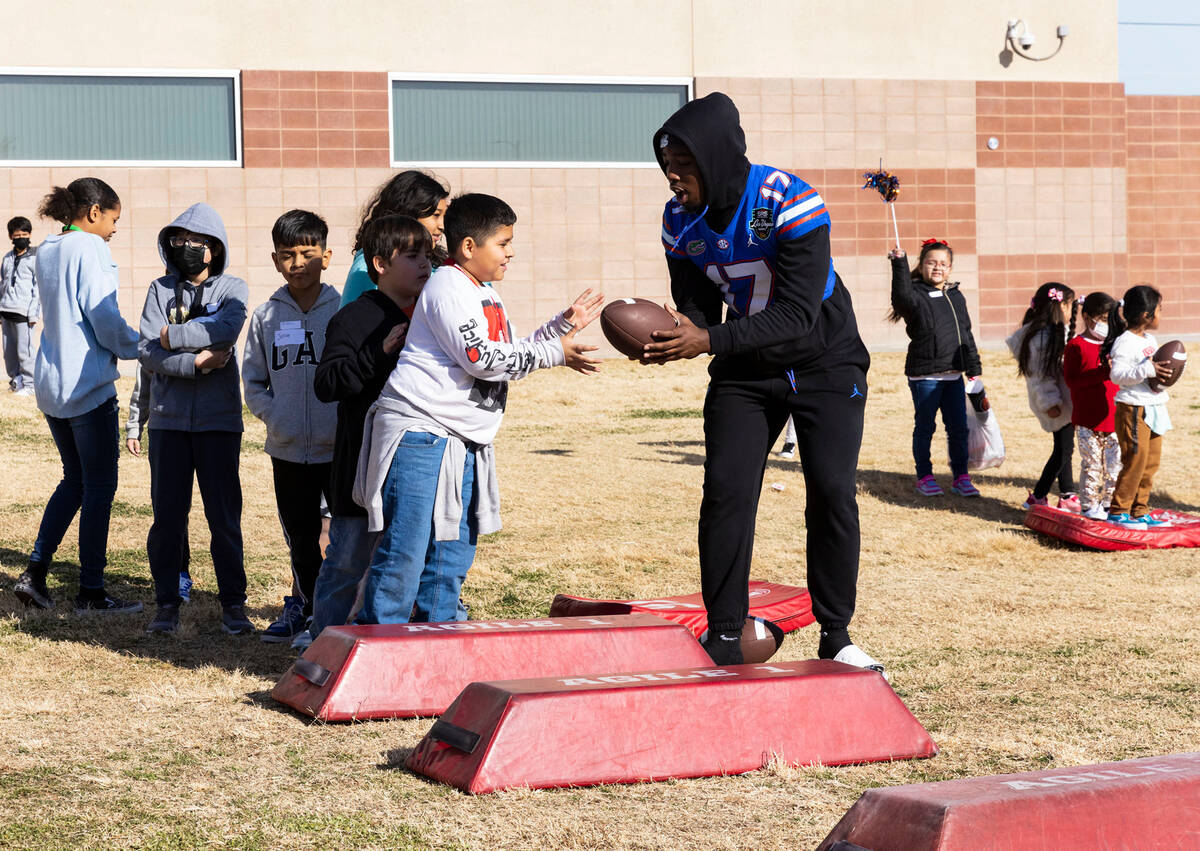 Florida Gators linebacker Scooby Williams hands the ball to C.P. Squires Elementary School stu ...