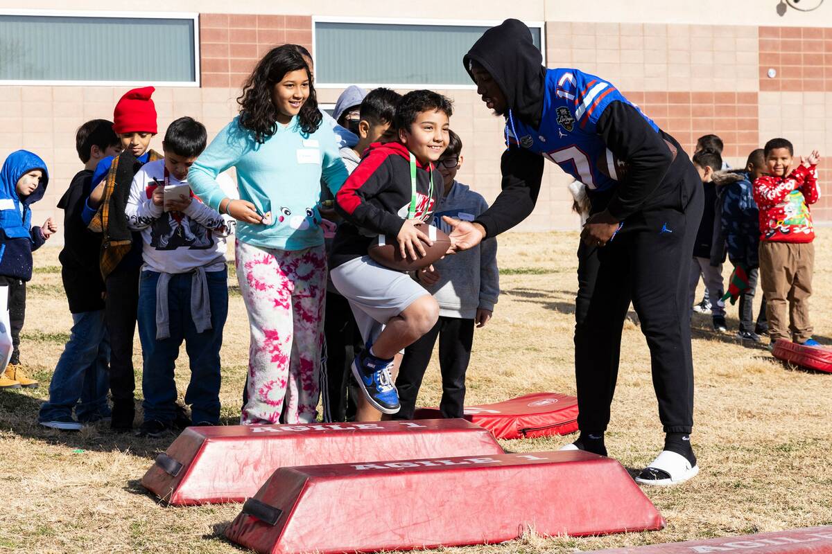 Florida Gators linebacker Scooby Williams hands the ball to C.P. Squires Elementary School stu ...