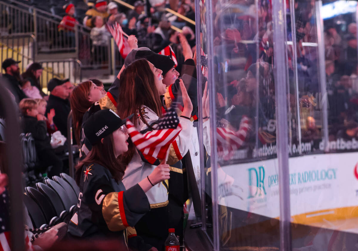 USA hockey fans cheer at the start of the first period of a rivalry hockey game against Canada ...