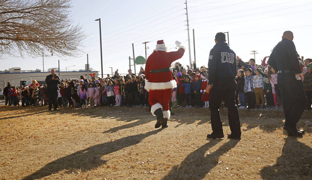 Santa Claus waves to the students after he arrived at Fay Herron Elementary School by helicopte ...