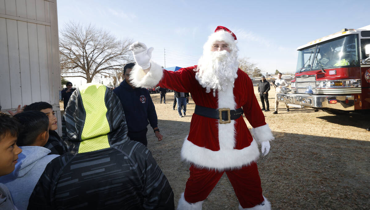 Santa Claus greets the students after he arrived at Fay Herron Elementary School by helicopter, ...