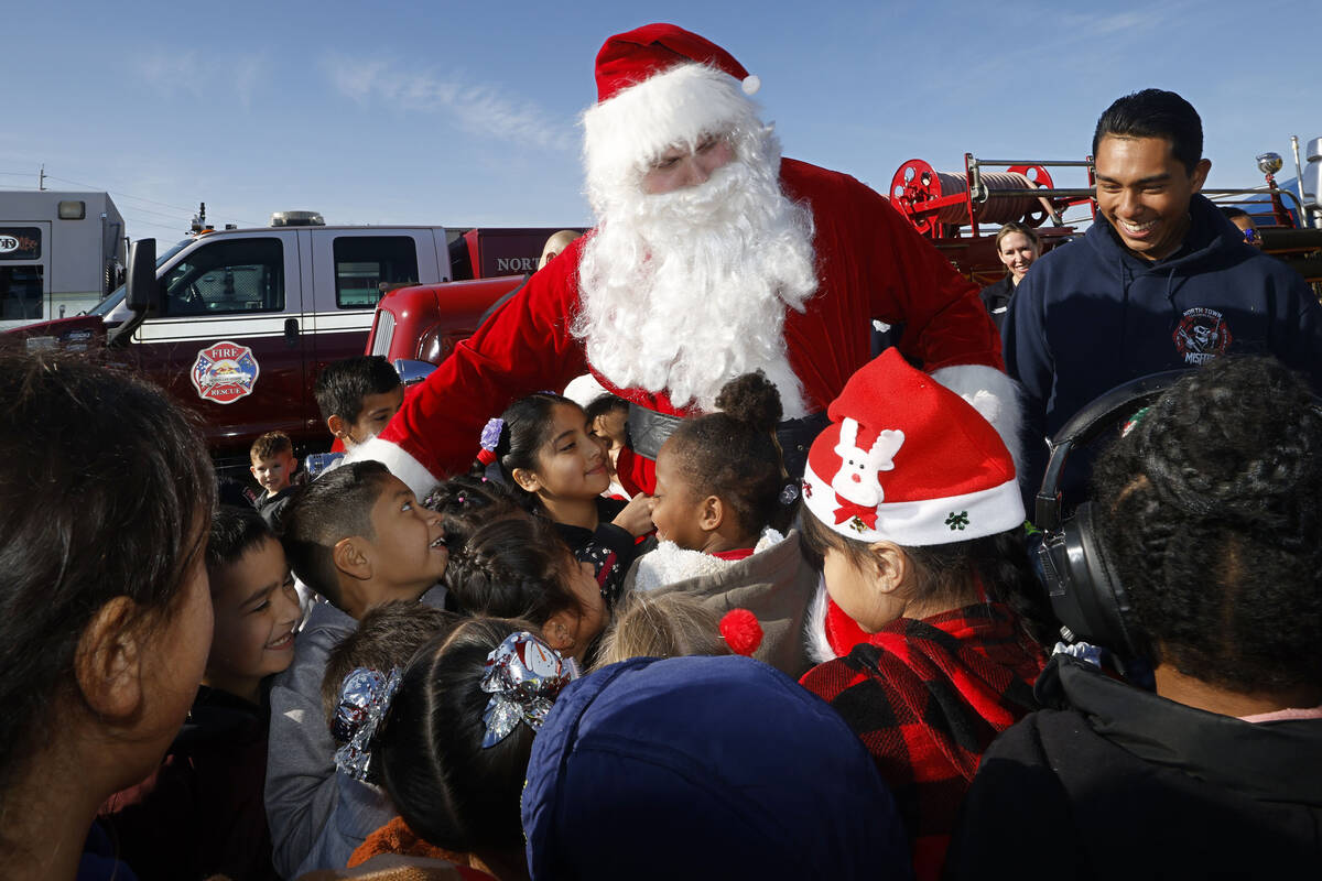 Santa Claus greets the students after he arrived at Fay Herron Elementary School by helicopter, ...