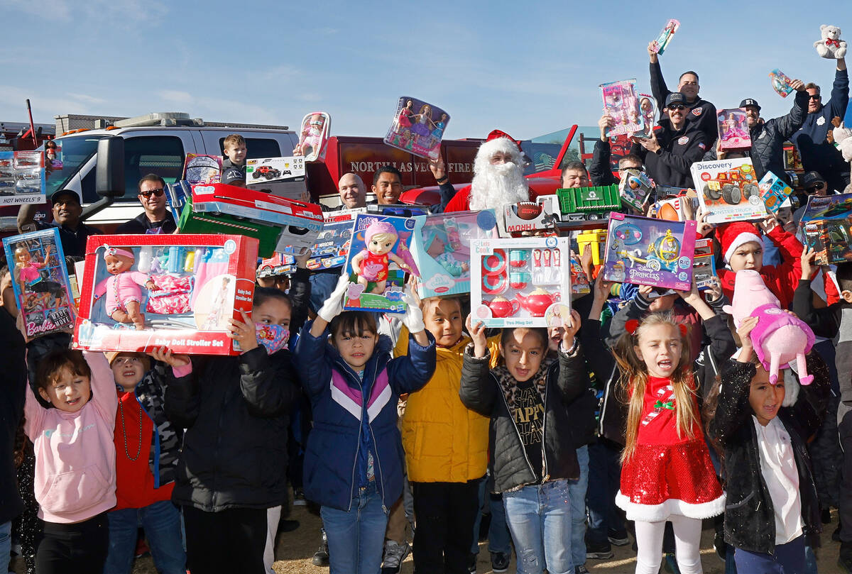 Herron Elementary School students show the toys that they just received while taking a photo wi ...
