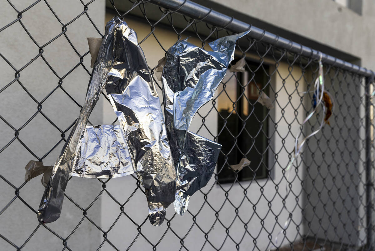 Morning light begins to illuminate deflated balloons on the fence surrounding the former Alpine ...