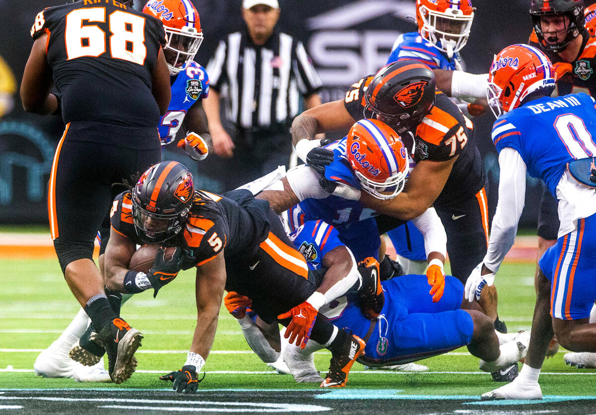 Oregon State Beavers running back Deshaun Fenwick (5) stretches for a few more yards wrapped up ...