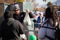 Gabriel Diaz, volunteer, passes out a bag of groceries to people during the Las Vegas Rescue Mi ...