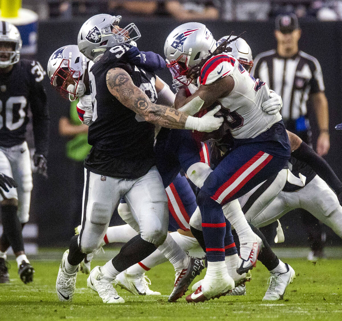 Raiders defensive end Maxx Crosby (98) fights to tackle New England Patriots running back Rhamo ...
