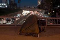 FILE - A homeless person's tent sits on a bridge over the 110 Freeway in Los Angeles, Wednesday ...