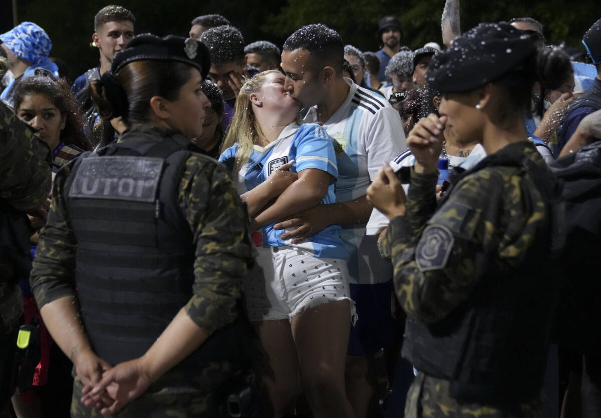 Fans kiss while waiting for the arrival of the Argentine soccer team that won the World Cup out ...