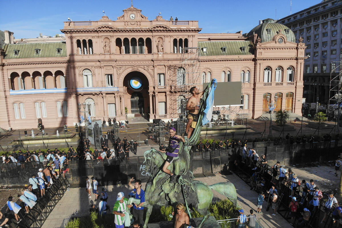 Soccer fans celebrating that Argentina won the World Cup tournament set a flag on a monument in ...