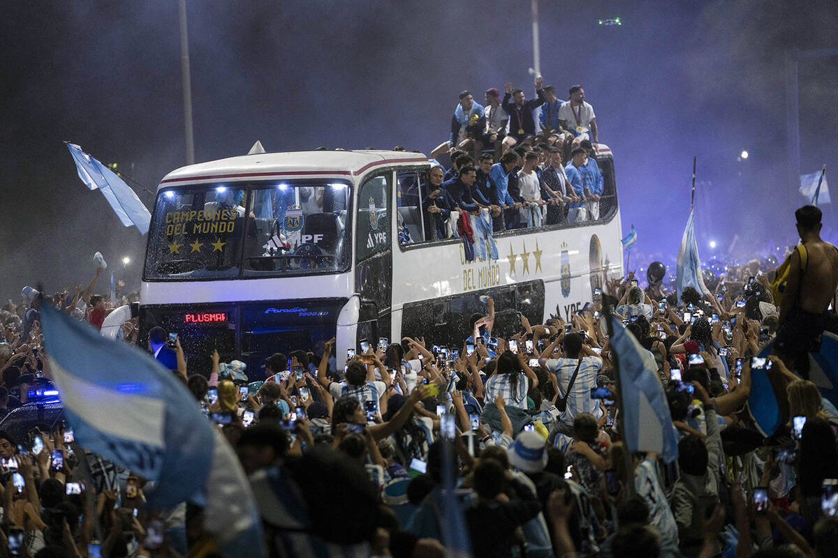 Soccer fans surround the bus taking the Argentine soccer team that won the World Cup to the Arg ...