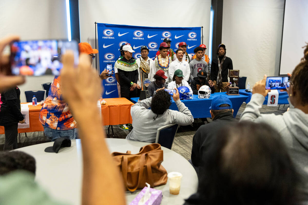 Students pose with their football head coach Brent Browner, center, during the National Signing ...