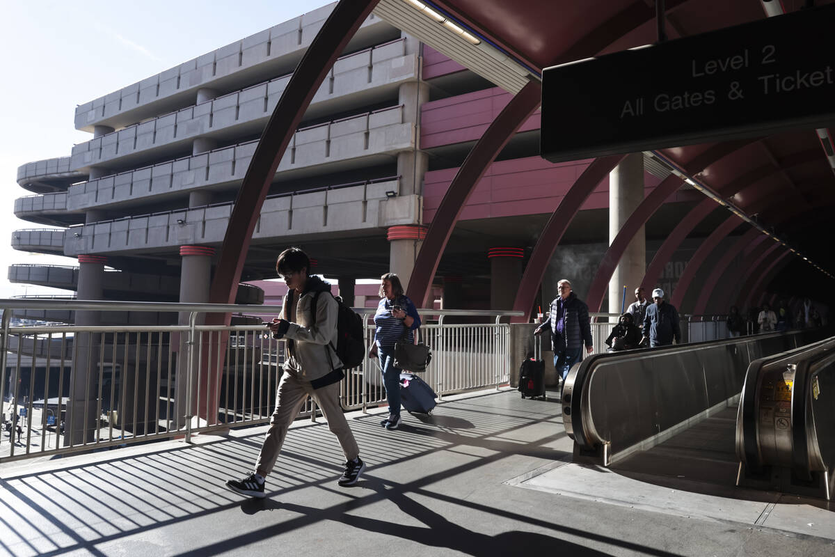 Travelers walk to the parking garage and ride share pickup area at Harry Reid International Air ...