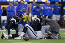 Raiders guard Alex Bars (64) is tended to by trainers during the first half of an NFL game aaga ...