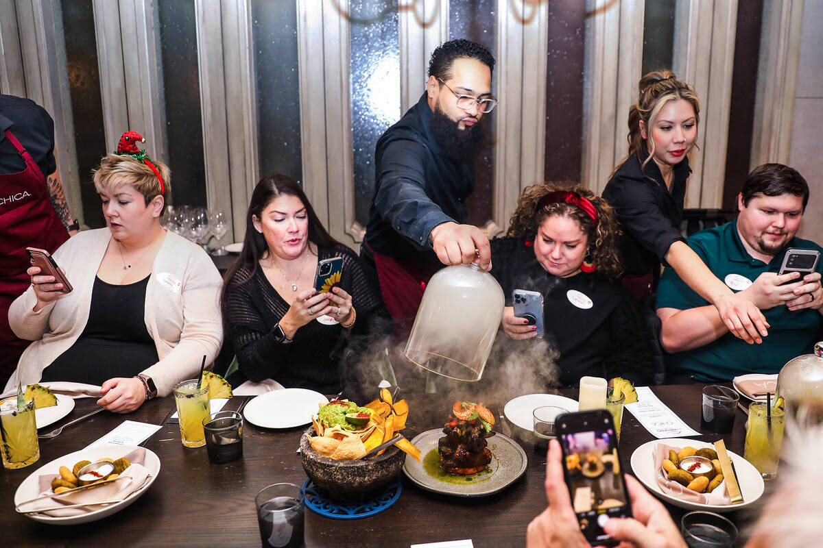 Server Lamar Graham showcases the baby back ribs “al pastor” dish to guests Sara Barlow, fr ...