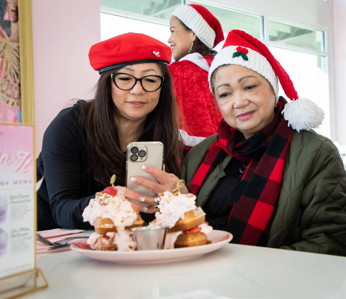 Portia Wigget, left, takes a photo of the Strawberry Shortcake Waffle at Cafe Lola on Friday, D ...