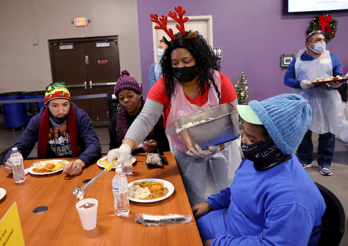 Volunteer LaMadrid Marquez pours marshmallows into hot chocolate for Messiah Woodard, 10, as hi ...