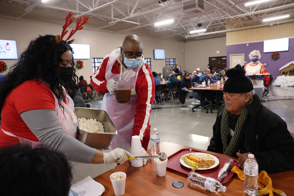 Volunteers LaMadrid Marquez and Wiley Barnes serve hot chocolate to John Schwartz, 54, during a ...