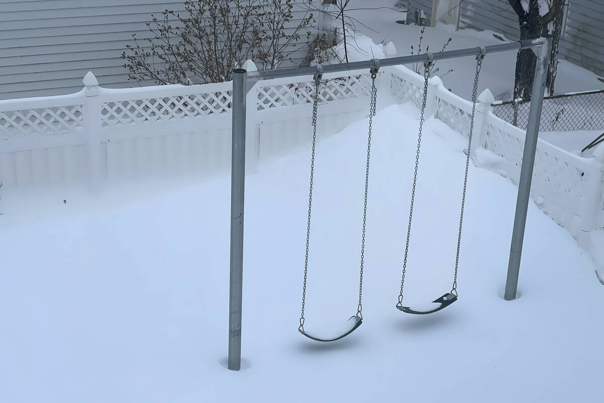 A snow drift nearly touches the bottom of two swings, Sunday, Dec. 25, 2022, in a neighborhood ...
