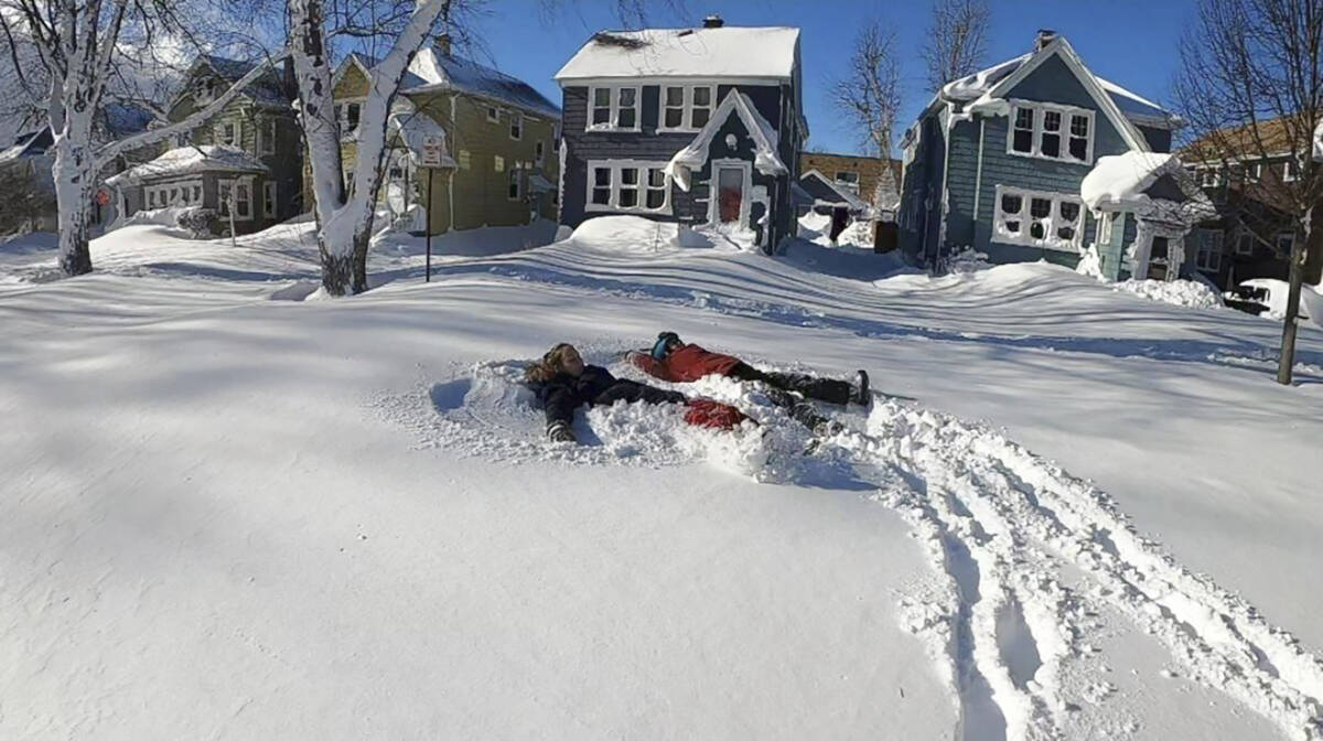 This photo provided by Clare Purcell shows two people making snow angels after a snowstorm in B ...