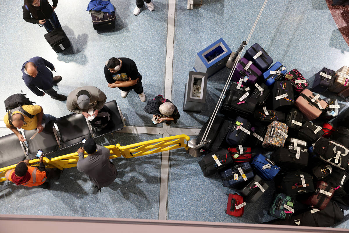 Travelers try to retrieve their luggage from cancelled and delayed flights in baggage claim of ...