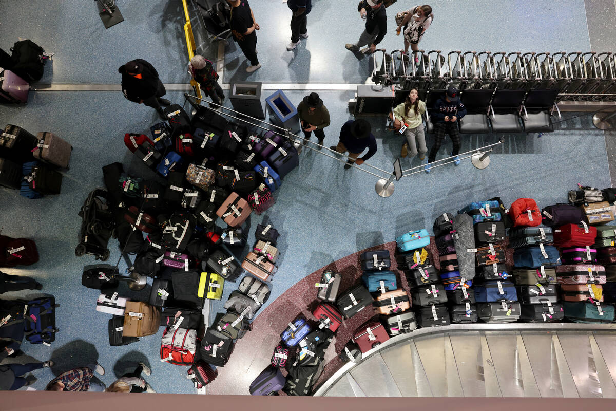 Travelers try to retrieve their luggage from cancelled and delayed flights in baggage claim of ...