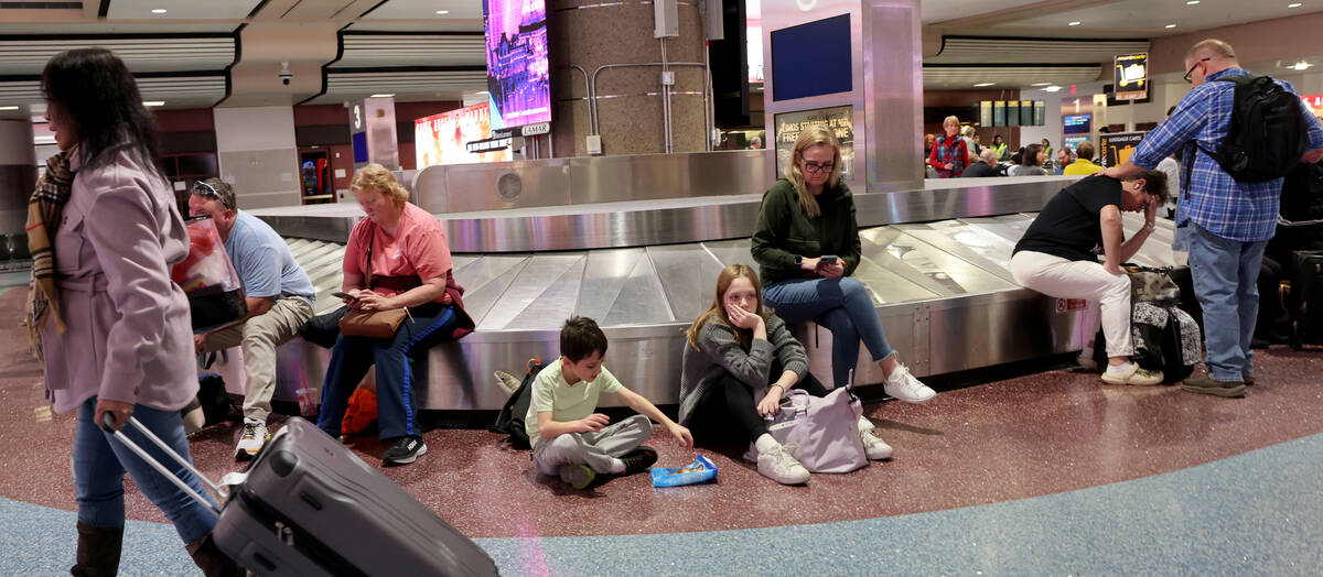 Travelers wait to retrieve their luggage from cancelled and delayed flights in baggage claim of ...