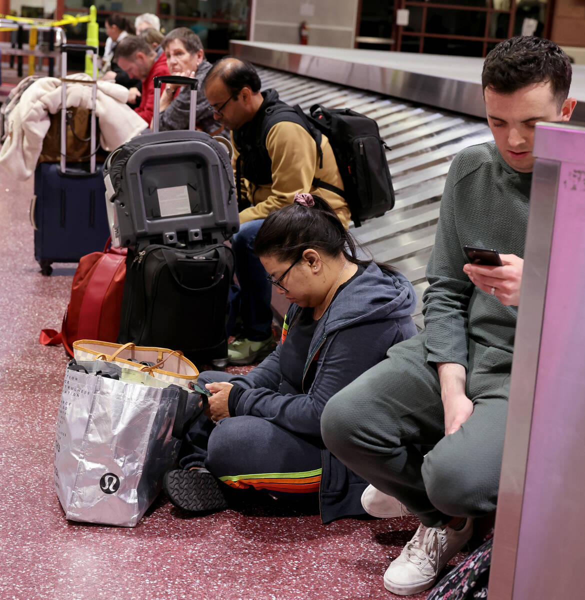 Travelers wait to retrieve their luggage from cancelled and delayed flights in baggage claim of ...