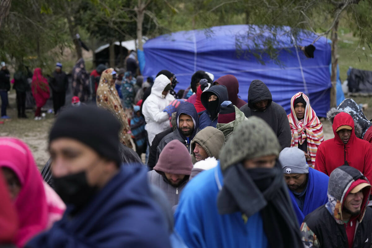 Migrants from Venezuela line up in the cold weather for hot drinks and food from volunteers at ...