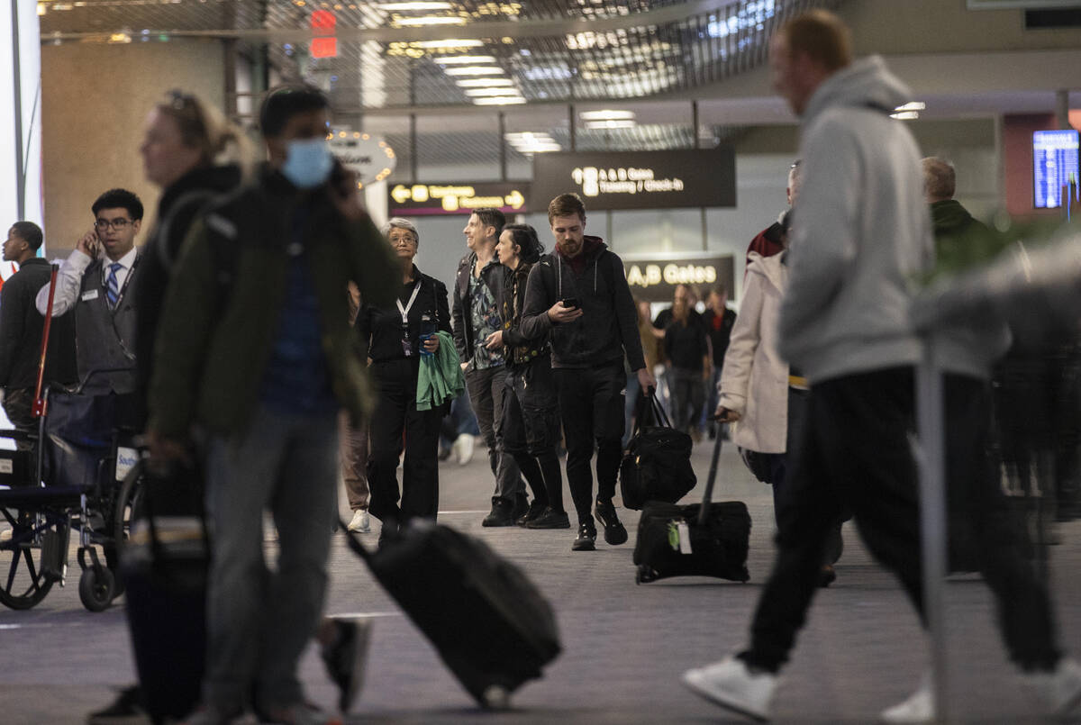 Travelers walk through terminal 1 at Harry Reid International Airport on Sunday, Nov. 27, 2022, ...