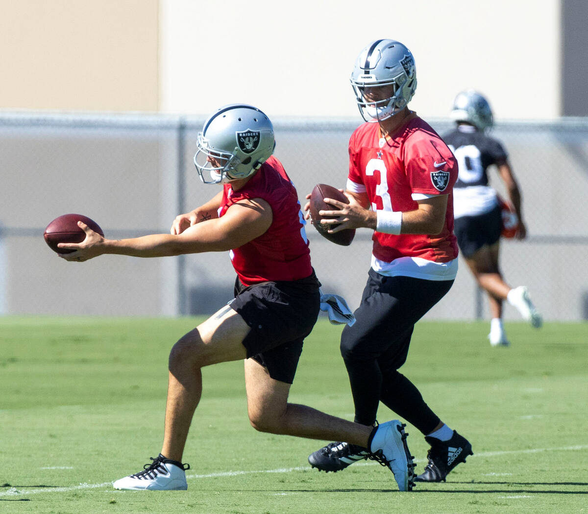 Raiders quarterbacks Derek Carr (4) and Jarrett Stidham (3) work on hand-offs during practice a ...