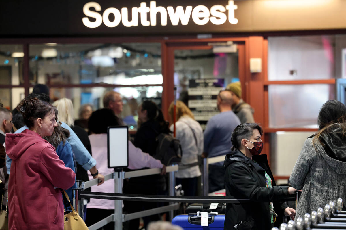 Passengers wait to retrieve their luggage from canceled and delayed flights in the Southwest ba ...
