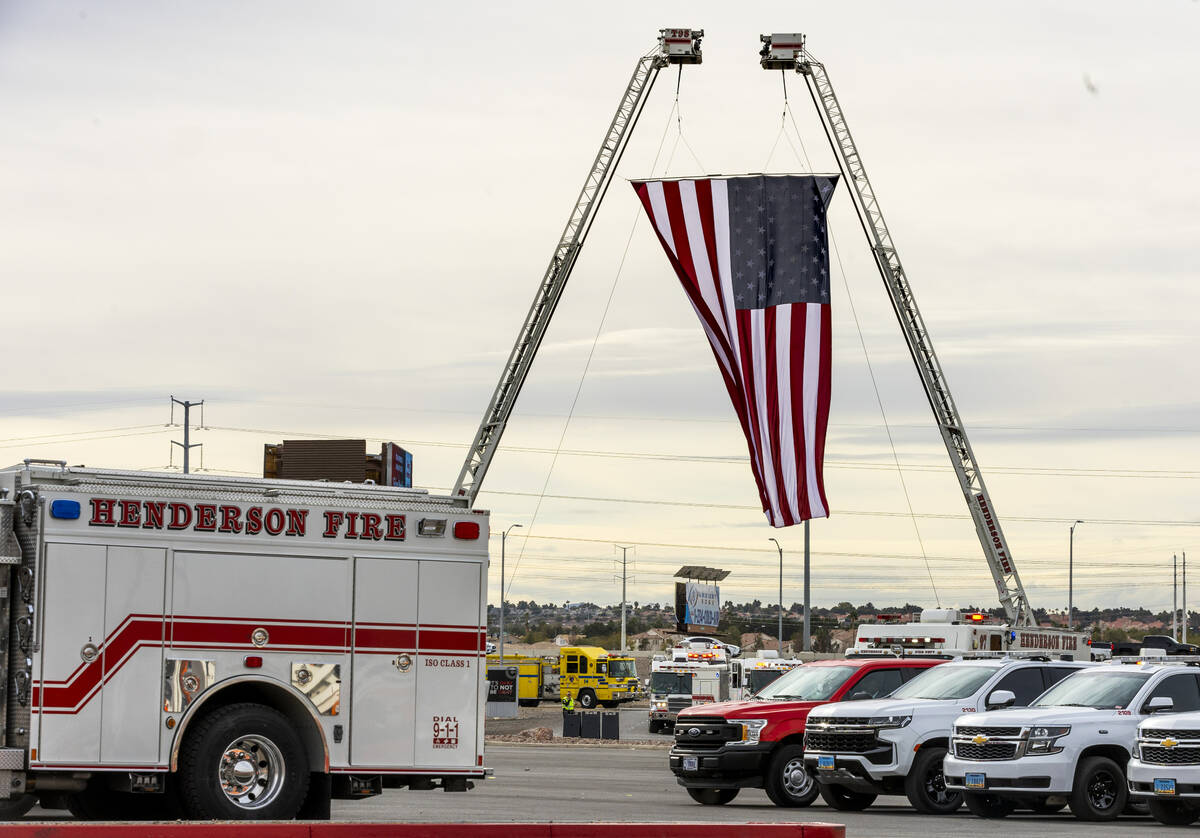 Emergency vehicles enter beneath a large American flag as Henderson Fire Department Engineer Cl ...