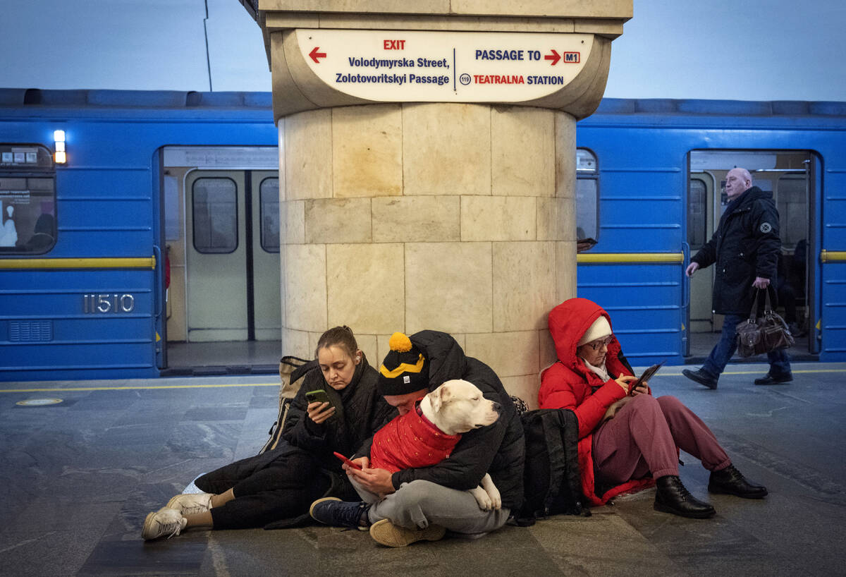 People sit in the subway station being used as a bomb shelter during a rocket attack in Kyiv, U ...