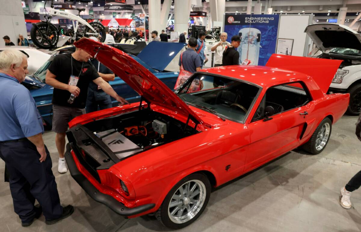 Conventioneers check out a 1965 Ford Mustang converted to an electric vehicle in the AEM EV boo ...