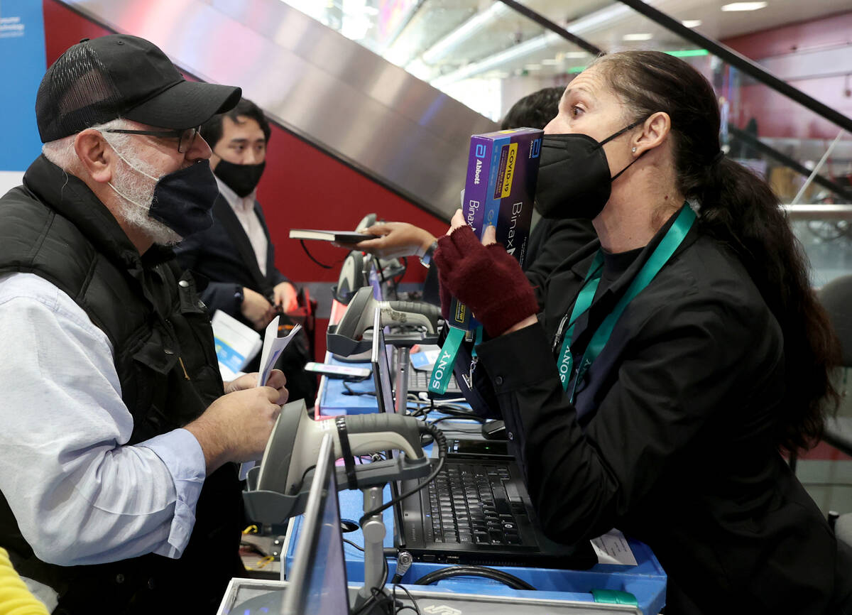 Stuart Honickman of New York picks up his CES badge and COVID-19 test kit from Mary Rauch after ...
