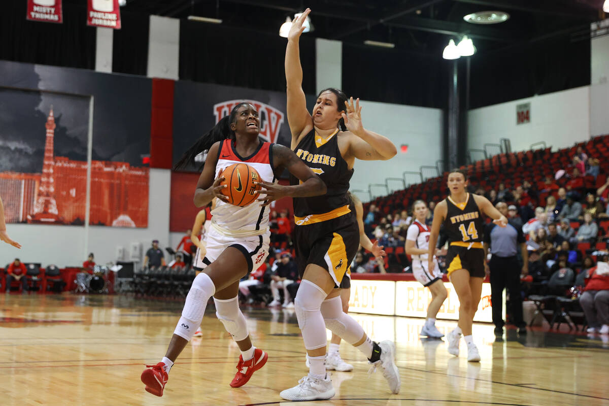 UNLV Lady Rebels center Desi-Rae Young (23) dribbles the ball to the basket under pressure from ...