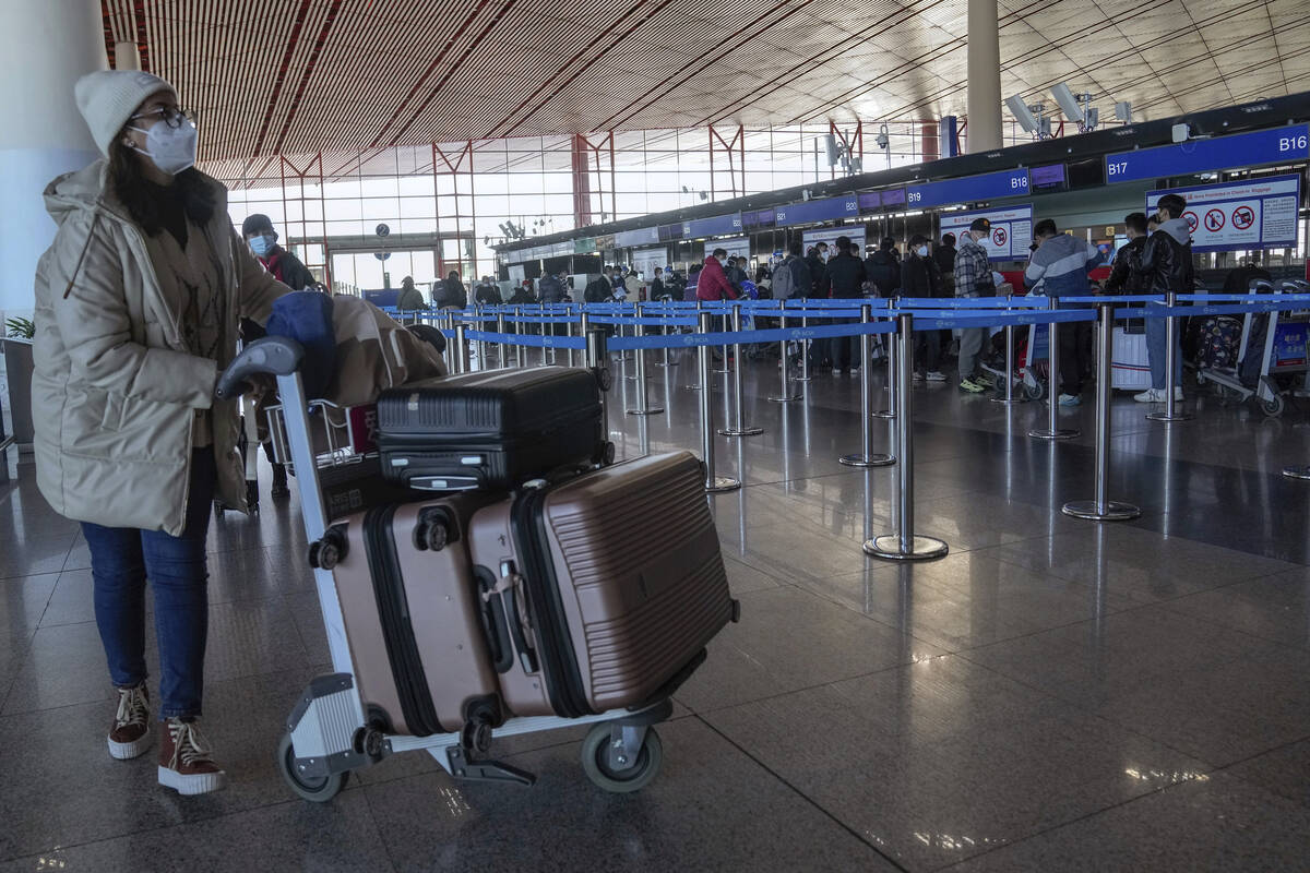 A masked traveler arrives at the international flight check in counter at the Beijing Capital I ...